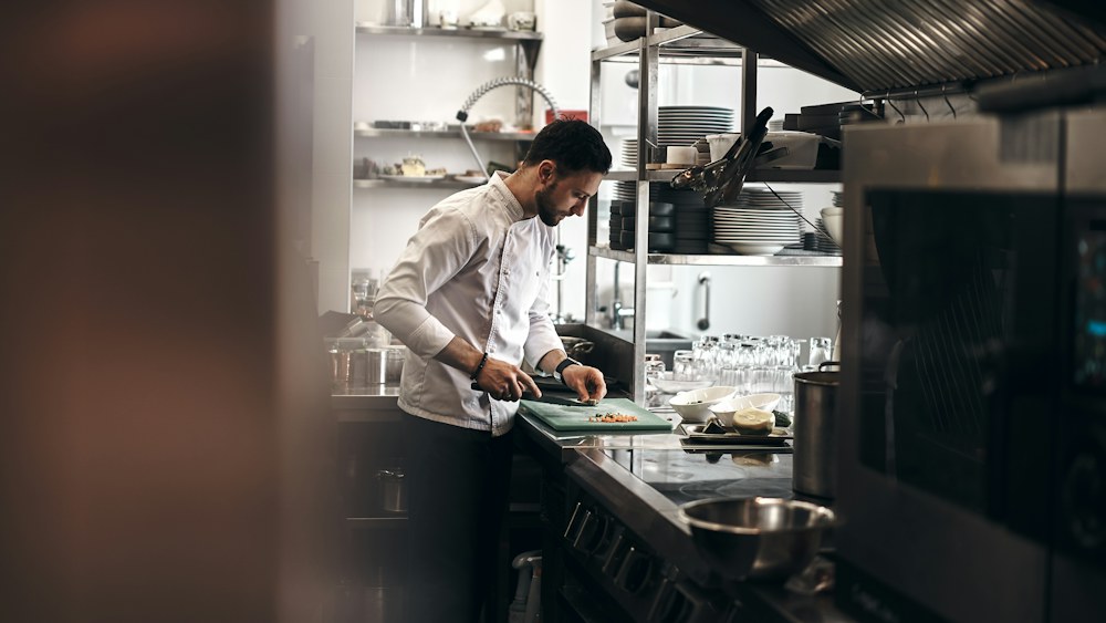 Un cuisinier prépare un plat dans sa cuisine.