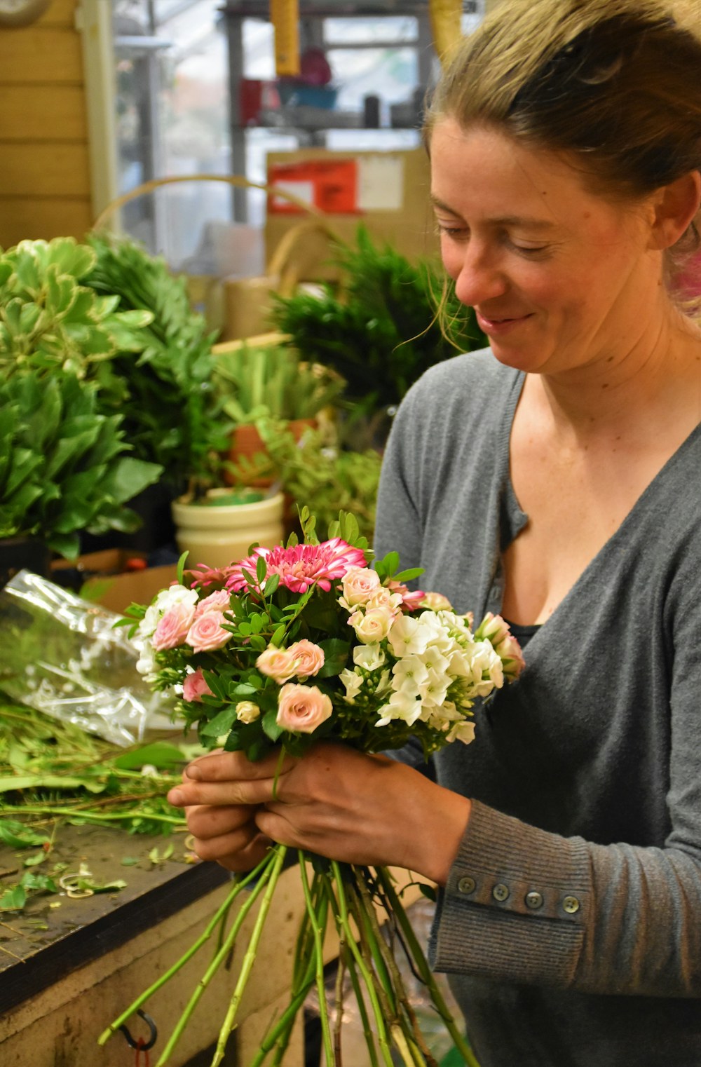 Une fleuriste compose un bouquet dans sa boutique.